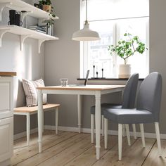 a kitchen table with two chairs and a potted plant on the window sill