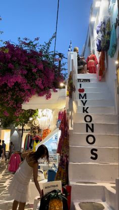 a woman in a white dress is standing on the steps to a store that sells clothes