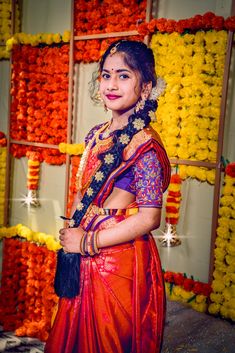 a woman in an orange and red sari posing for the camera with her hands on her hips