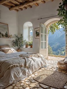 a bedroom with an arched window and stone flooring is pictured in this image, overlooking the mountains