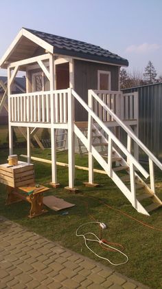 there is a small wooden house with stairs to the top and bottom floors on grass