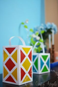 two colorful boxes sitting on top of a table next to a vase with flowers in it