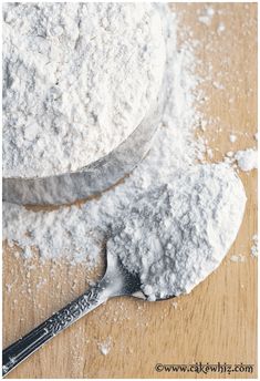 two spoons filled with powder on top of a wooden table