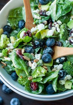 a salad with blueberries, avocado and feta cheese in a bowl