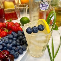 blueberries, raspberries and lemons sit on a table with drinks in glasses