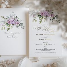 two wedding cards with flowers and greenery on them, sitting next to each other