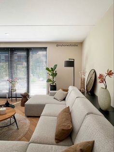 a living room filled with furniture and a large window covered in blinds on the windowsill