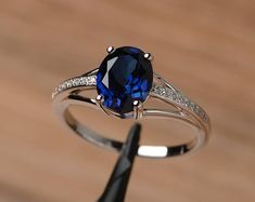 a ring with a blue stone and diamond set in it on top of a wooden table