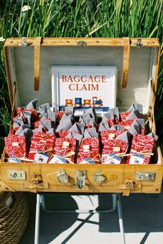 an open suitcase with bags of luggage in it sitting on a table next to some grass