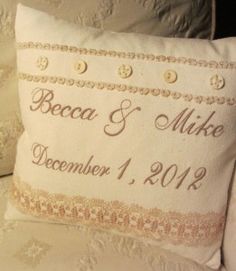 a wedding pillow on a couch with buttons and lace around the edges that says, beca & mike december 1, 2010