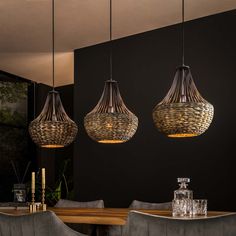 three lights hanging from the ceiling above a dining room table with grey upholstered chairs