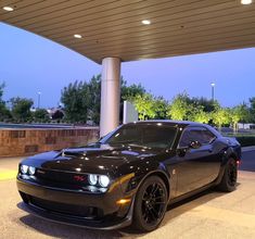 a black sports car parked in front of a gas station