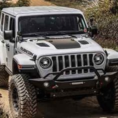 a white jeep driving down a dirt road