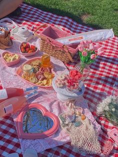 a picnic blanket with food on it and flowers in the basket next to some water