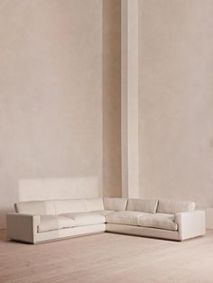 a white couch sitting on top of a hard wood floor next to a tall wall