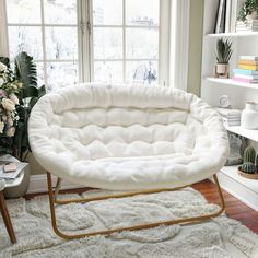 a white chair sitting on top of a rug next to a window