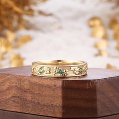 a close up of a gold ring on top of a wooden box with flowers and leaves