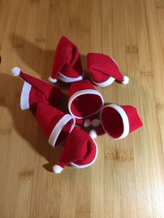 four red and white santa hats sitting on top of a wooden table