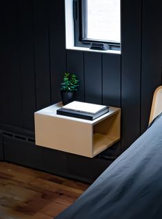 a bedroom with black walls and wooden flooring has a small white table next to the bed