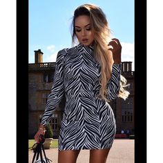 a woman in a zebra print dress is holding a handbag and posing for the camera