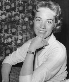 black and white photograph of a woman sitting at a table with her hand on her chin