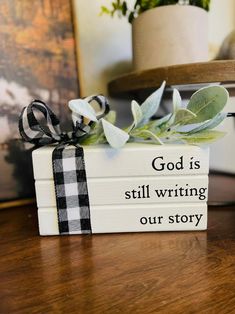 a book with a ribbon on it sitting on top of a table next to a potted plant