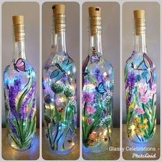 three glass bottles with flowers and butterflies in them, one has a light inside the bottle