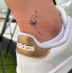 a woman's foot with a small tattoo on the ankle and a dandelion