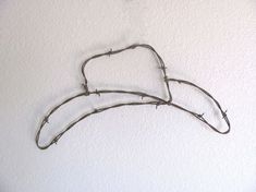 barbed wire hanging on the wall in front of a white wall with two hearts shaped like branches