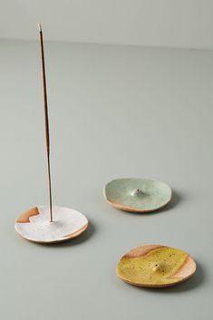 three small plates with sticks sticking out of them on a gray surface, one is empty and the other two are not