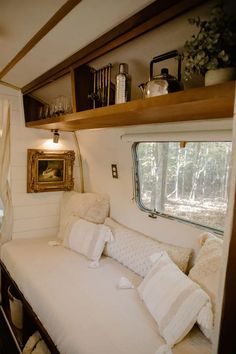 there is a couch in the living room with pillows on it and shelves over the window