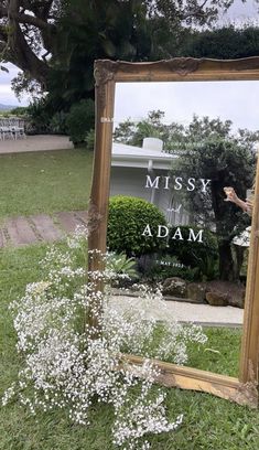 a mirror sitting on top of a grass covered field next to a tree and white flowers