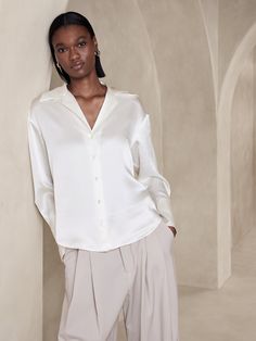 We used a modern silhouette to update this resort shirt using our easy-care silk charmeuse, selected for its beautiful drape and satin-style shine.  Relaxed fit.  Exaggerated resort collar.  Troca shell button front.  Long cuffs.  Shirttail hem.  Relaxed fit.  Long sleeves.  Below-hip length.  Body length (size S): Regular 22" Sleeve length from center back: Regular 16" Luxury White Blouse For Vacation, Affordable White Vacation Shirt, Princess Diana White Shirt, Over Size Silk Shirt, Vintage Suede Jacket, Satin Style, Resort Shirt, Sleeveless Tops Summer, Banana Republic Skirt