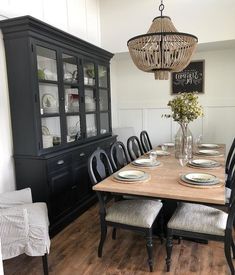 the dining room table is set with place settings for six people and has a chandelier hanging over it