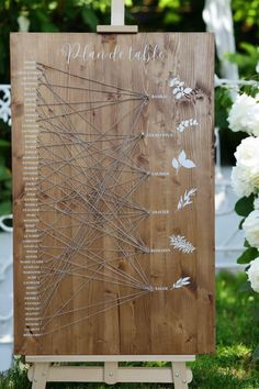 a wooden sign with pins on it and white flowers in the backgroung