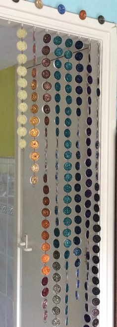 there are many different colored buttons hanging on the wall in front of this door window