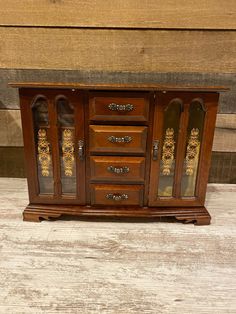 an old wooden cabinet with glass doors on it's front and side panels that have gold designs on them