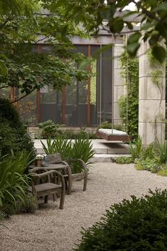 an outdoor area with benches, plants and graveled ground in front of a building