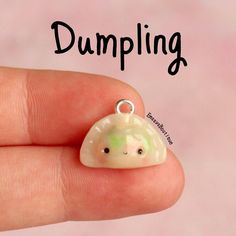 a hand holding a tiny white and green object with the words dumpling on it