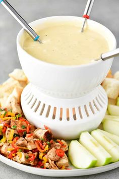 a white bowl filled with soup next to sliced apples and crackers on a plate