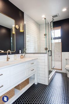 a bathroom with black and white tile flooring, gold fixtures and a large mirror above the sink