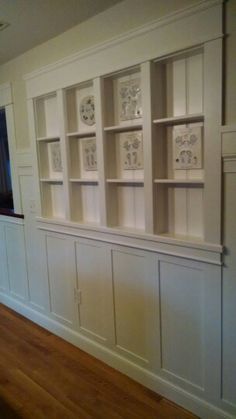 an empty room with white bookcases and wood flooring on the side wall