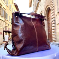 "This bag has been made of the best genuine leather by local master crafters of Florence in Italy, designed for women who only accept premium Italian quality and luxury leather bags and modern Italian fashion. . Sizes: Width: 27 cm / 10.7 inches Height: 31 cm / 12.2 inches Depth: 13 cm / 5.2 inches Color: Dark Brown . The story of this bag: In the enchanting city of Florence, renowned for its artistic heritage and exquisite craftsmanship, a tale unfolds about an elegant leather bag that captures the essence of Italian luxury. Handcrafted with utmost care and attention to detail, this premium leather bag embodies the timeless allure of Florence. Every stitch, every fold, and every delicate touch in the creation of this Florence leather bag is a testament to the skilled artisans who pour the Italian Leather Bags In Cognac, Italian Leather Bags In Cognac Color, Leather Backpack For Office, Elegant Leather Shoulder Bag With Leather Backing, Elegant Brown Leather Backpack For Daily Use, Elegant Daily Use Shoulder Bag With Leather Backing, Luxury Italian Brown Shoulder Bag, Elegant Leather Hobo Crossbody Bag, Elegant Soft Leather Shoulder Backpack