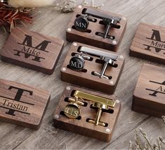 four wooden cufflinks with engraved initials on them, sitting on top of a table