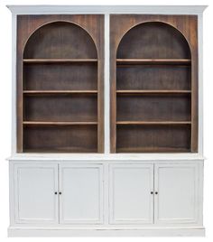 an old white bookcase with two arched doors