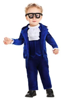 a little boy dressed up in a blue suit and black glasses with his hands out