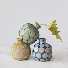 three vases with different designs on them, one has a plant in the middle