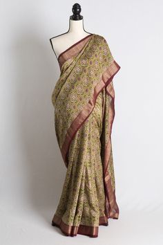 Ajrakh Printed Chanderi Cotton Silk Saree with Zari Border in Green and Maroon The fall pico is done on the saree and the blouse piece is cut and separated from the saree.  Color - Green and Dark Red. Fabric - Cotton Silk. Technique - Printed. Blouse Piece - Yes (cut & separated). Fall / Pico - Yes. Note: There may be minor variations in the shade of the product. Colors/textures show differently based on lighting, gadget settings, etc. Any displacements to stones, sequins, beads or embroidery ca Bandhani Print Jamawar Saree, Traditional Drape Jamawar Saree With Bandhani Print, Traditional Jamawar Saree With Bandhani Print, Jamawar Bandhani Print Saree, Festive Kalamkari Print Pre-draped Saree In Slub Silk, Fitted Jamawar Saree For Navratri, Traditional Jamawar Bandhani Print Wear, Fitted Chanderi Saree With Kalamkari Print, Fitted Traditional Wear With Kalamkari Print For Puja