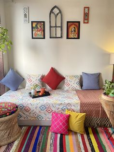 a bed with colorful blankets and pillows in a room filled with pictures on the wall