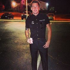 a police officer standing in the middle of a parking lot with his hands on his hips